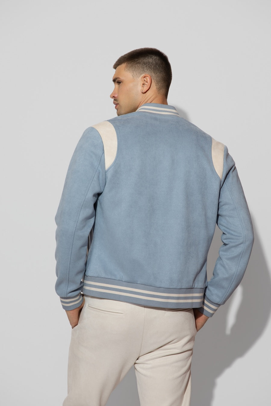 Back profile of MONFRÈRE Jeter Varsity Suede Carolina men's blue soft faux suede stretch fabric varsity jacket.