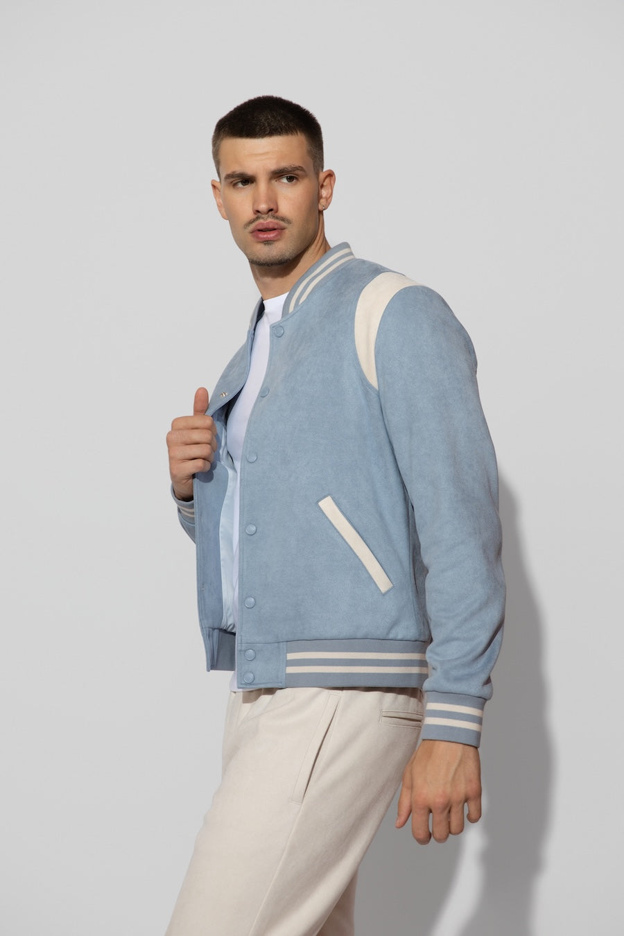 Side profile of MONFRÈRE Jeter Varsity Suede Carolina men's blue soft faux suede stretch fabric varsity jacket.